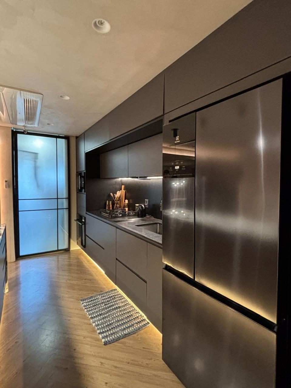 Cozinha planejada com refrigerador inox e porta em serralheria com vidro canelado