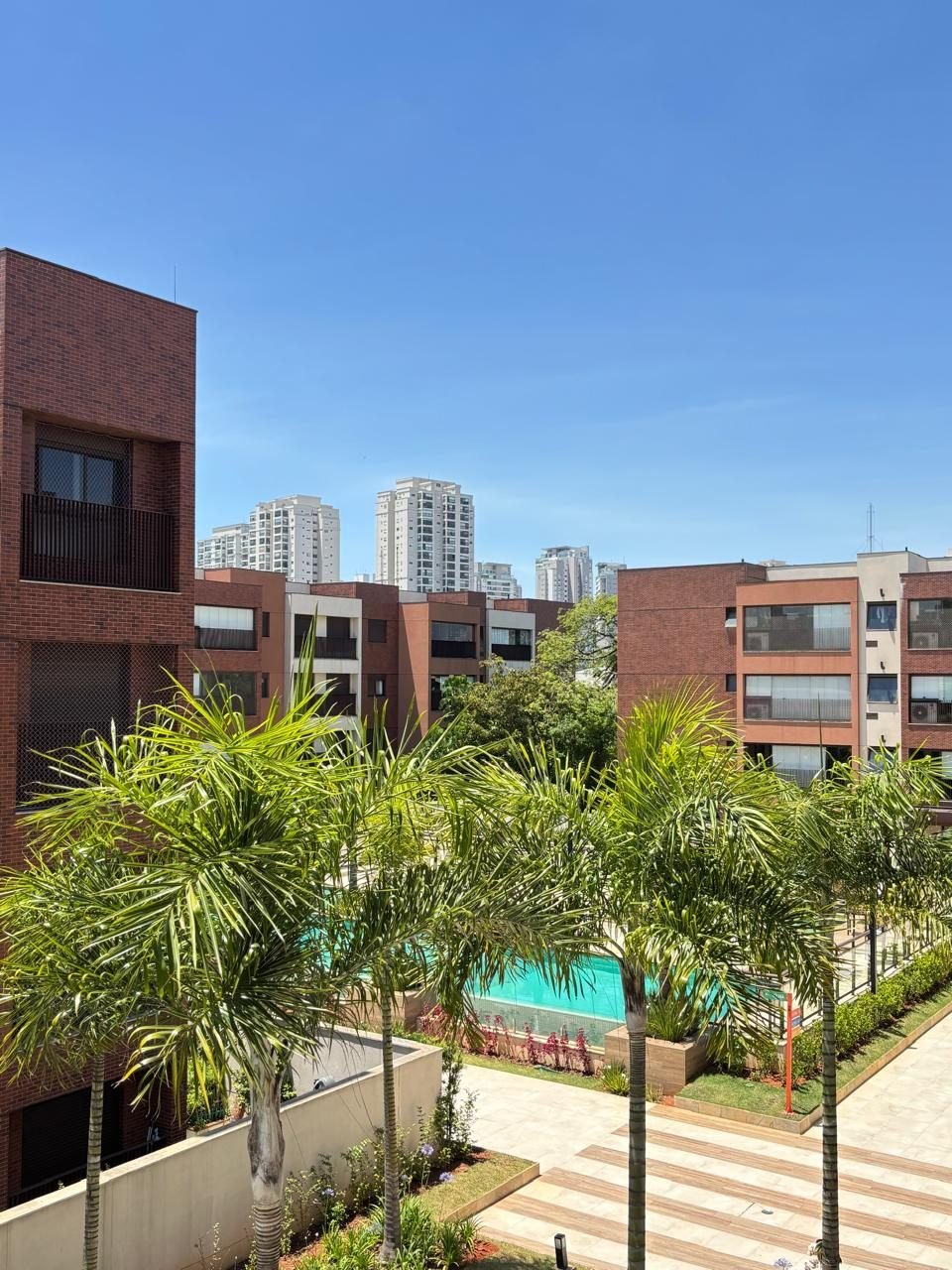Vista da piscina e do paisagismo com palmeiras do Condomínio Las Villas Ipiranga