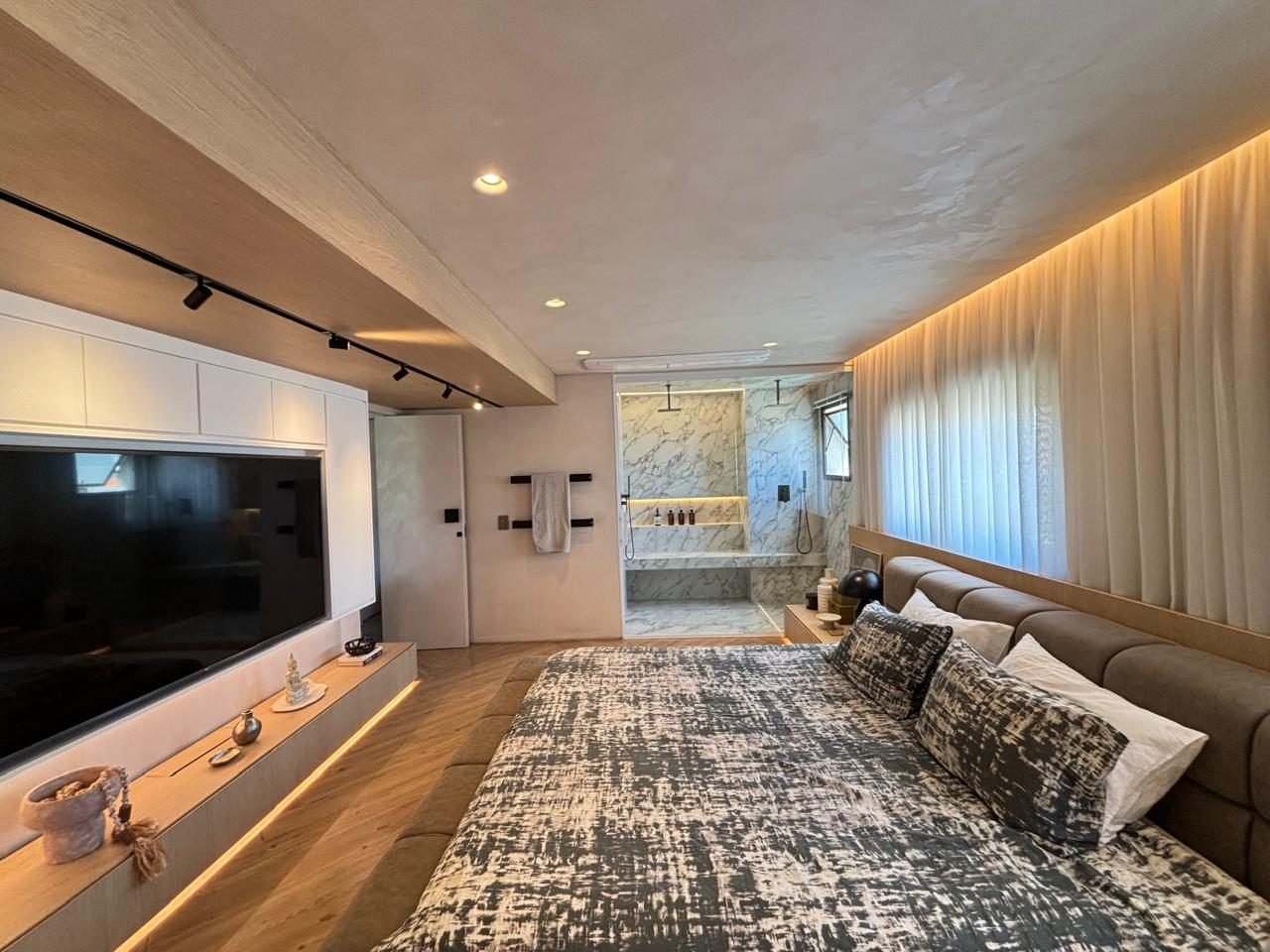 Suíte master com painel de TV e acesso ao banheiro